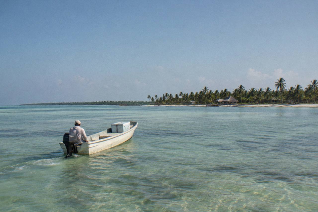 Sian Ka'an: Boca Paila lagoon flats with a small boat and Punta Allen palm beach